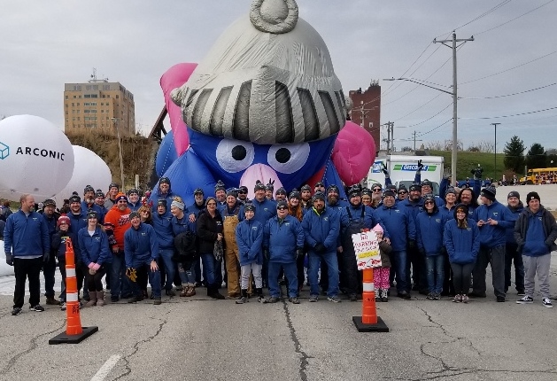 Image is picture of group of parade walkers in matching blue sweaters bearing the logo 